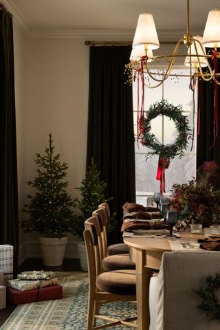 A pair of twin potted Christmas trees in the corner of a dining room