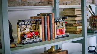 Lego Hogwarts Express Book Nook laid out between leather-bound books on a shelf