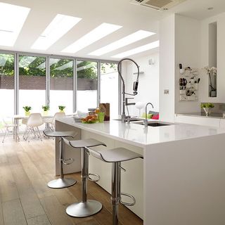white kitchen with large island unit and bar chairs
