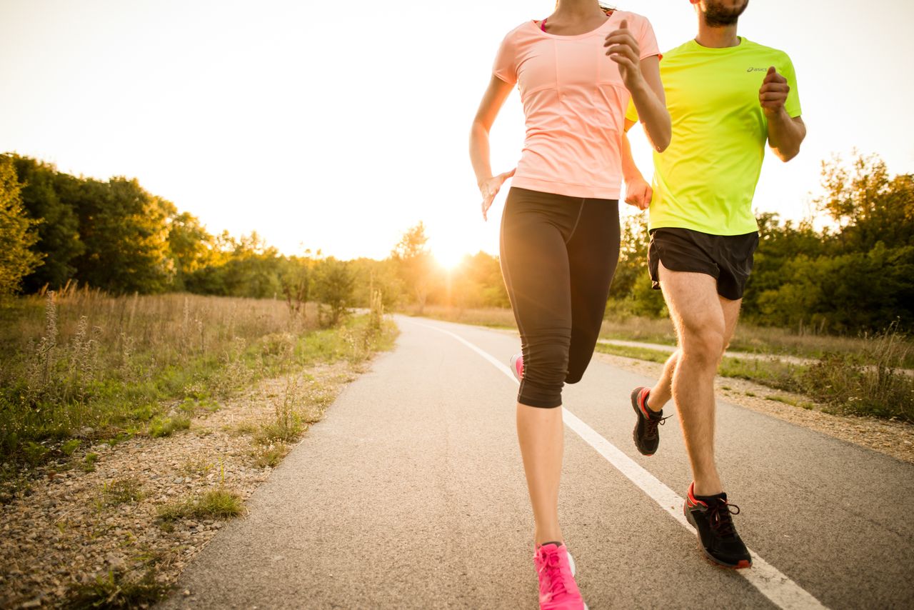 Detail of young people jogging together in nature with sun setting behind them.