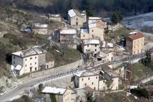 The peloton makes its way through a snow-dusted town