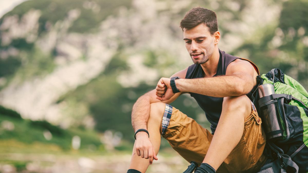 Man in hiking gear checking smartwatch