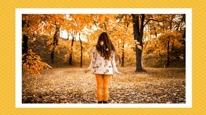 a woman in a sweater embracing the changing leaves, meant to symbolize the fall equinox 2023