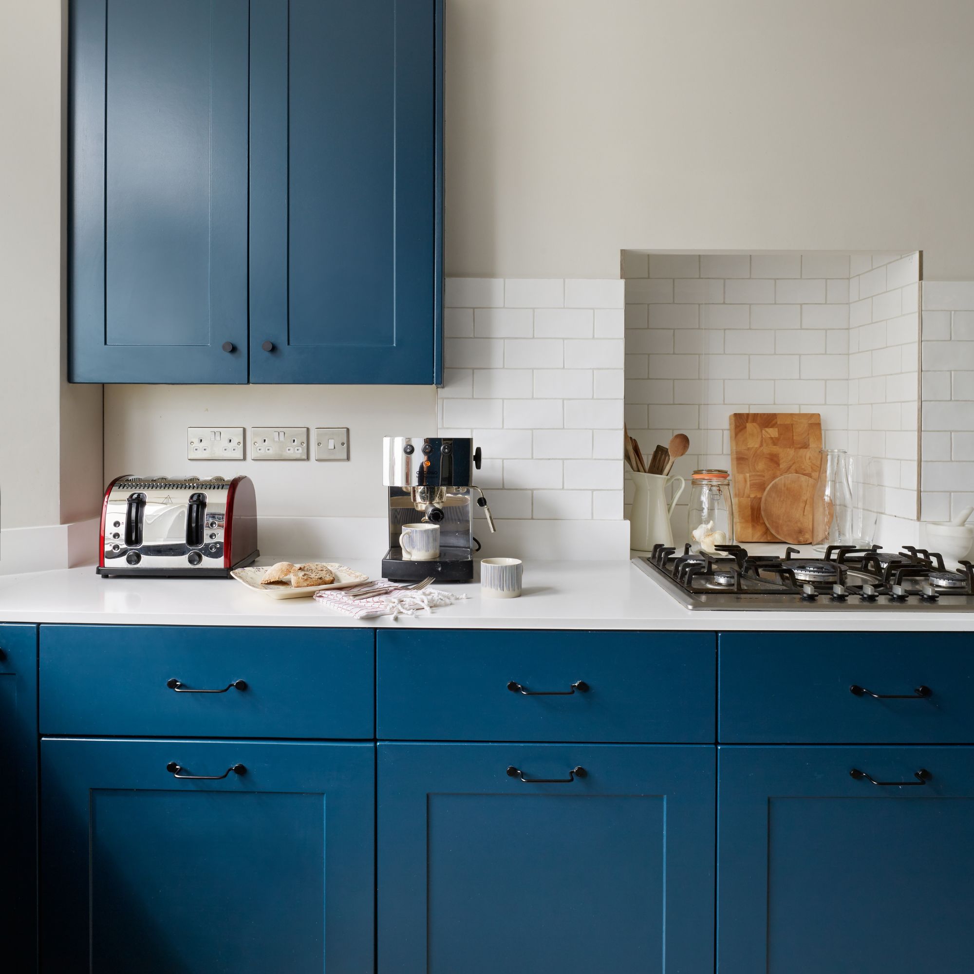 white painted kitchen with white tiles on the wall and blue kitchen cupboards