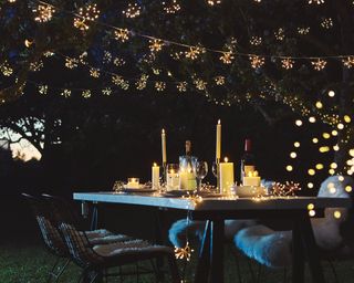 A Christmas outdoor dining scheme with candles and starburst lights