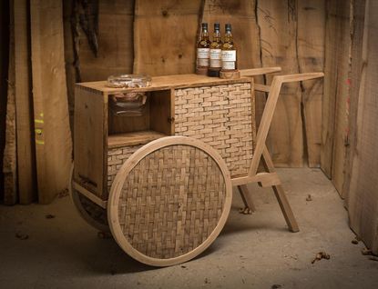 Weaved wood drink trolley. On top of it, there are 3 bottles of The Glenlivet whiskey.