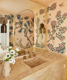 bathroom with floral wallpaper and large mirror above a stone basin