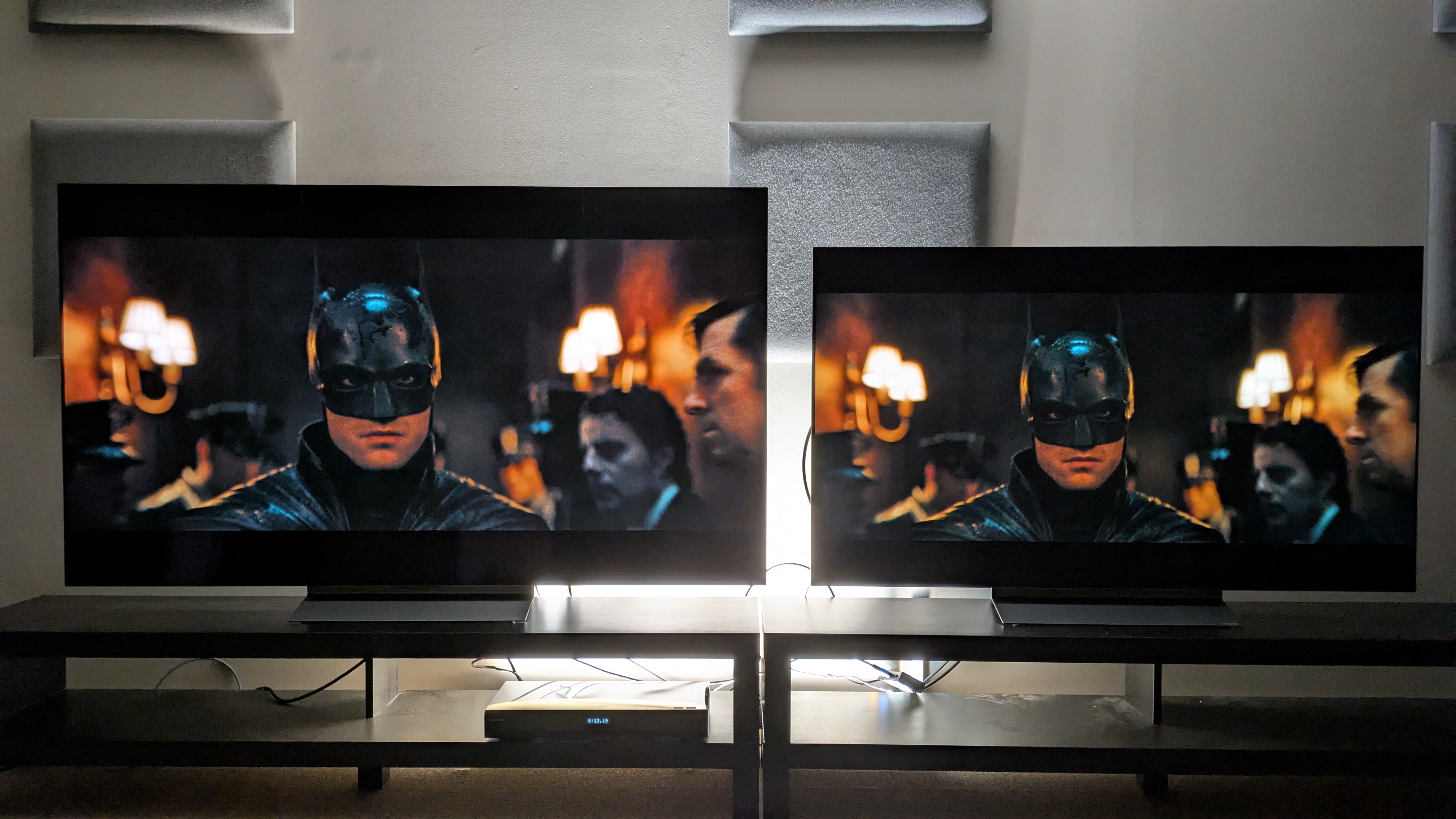 LG C6 (left) and LG C5 (right) OLED TVs showing Batman walking down a dim hallway. Both TVs again have strong contrast but the C6's is more refined with punchier lights and better shadow detail 