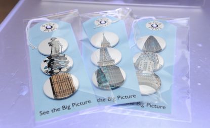 A photo of the gift tags with the same design. The tags have three pin badges packaged each depicting famous London landmarks including: Big Ben, the BT Tower, Tower Bridge, the Shard. 