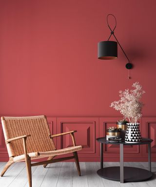 Living room with bright red walls, a rattan chair and coffee table