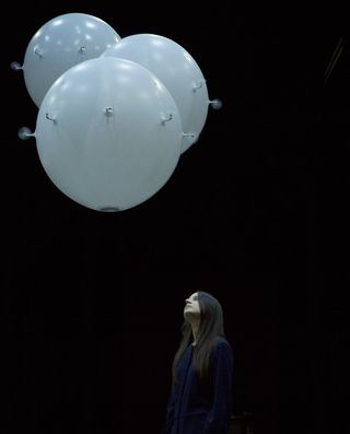 Woman looking up at three large spheres