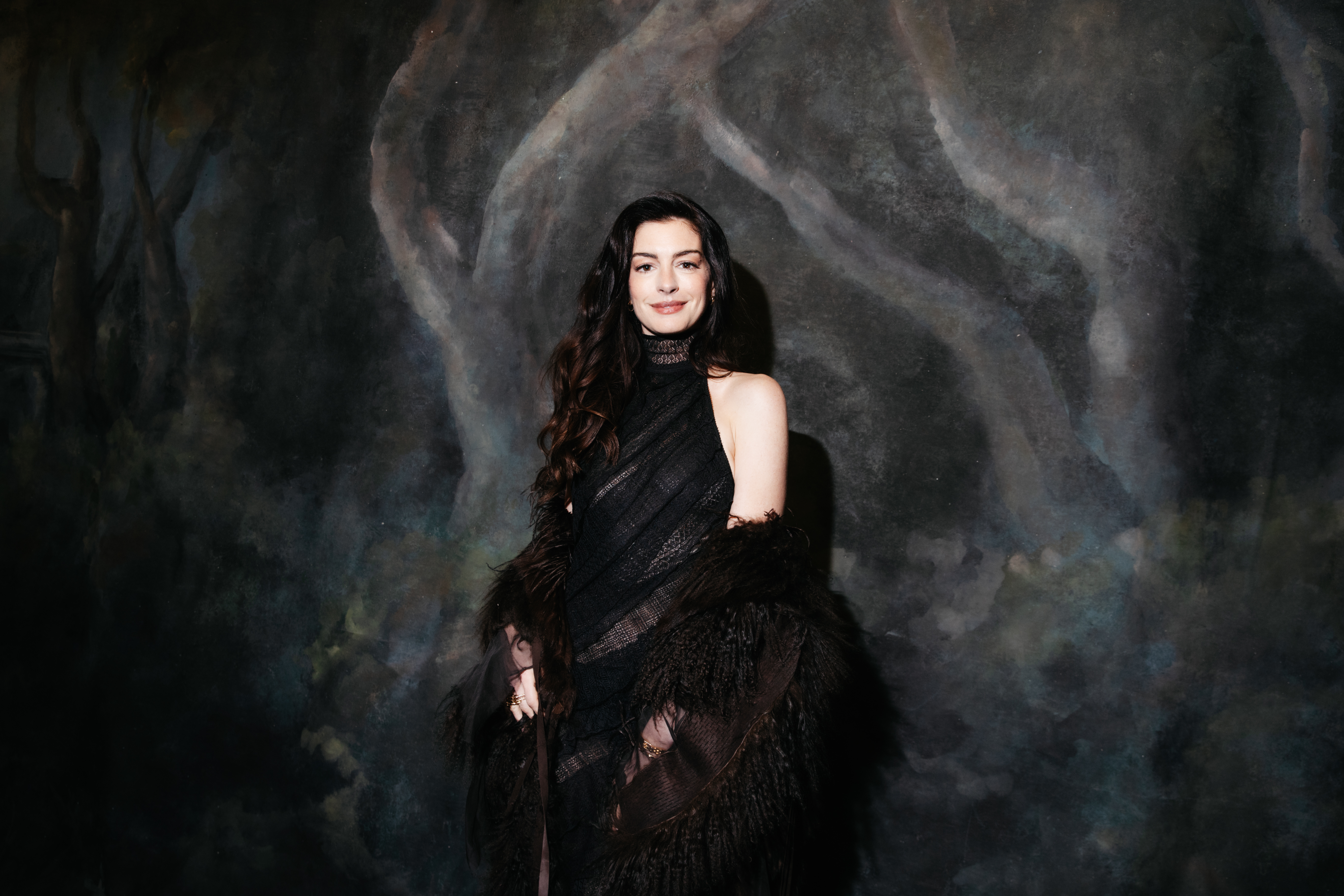 a white woman with long, dark hair posing in front of a dark background