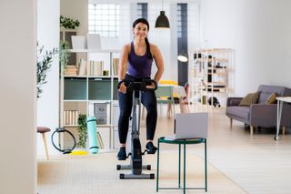 a woman on an exercise bike in a basement or apartment