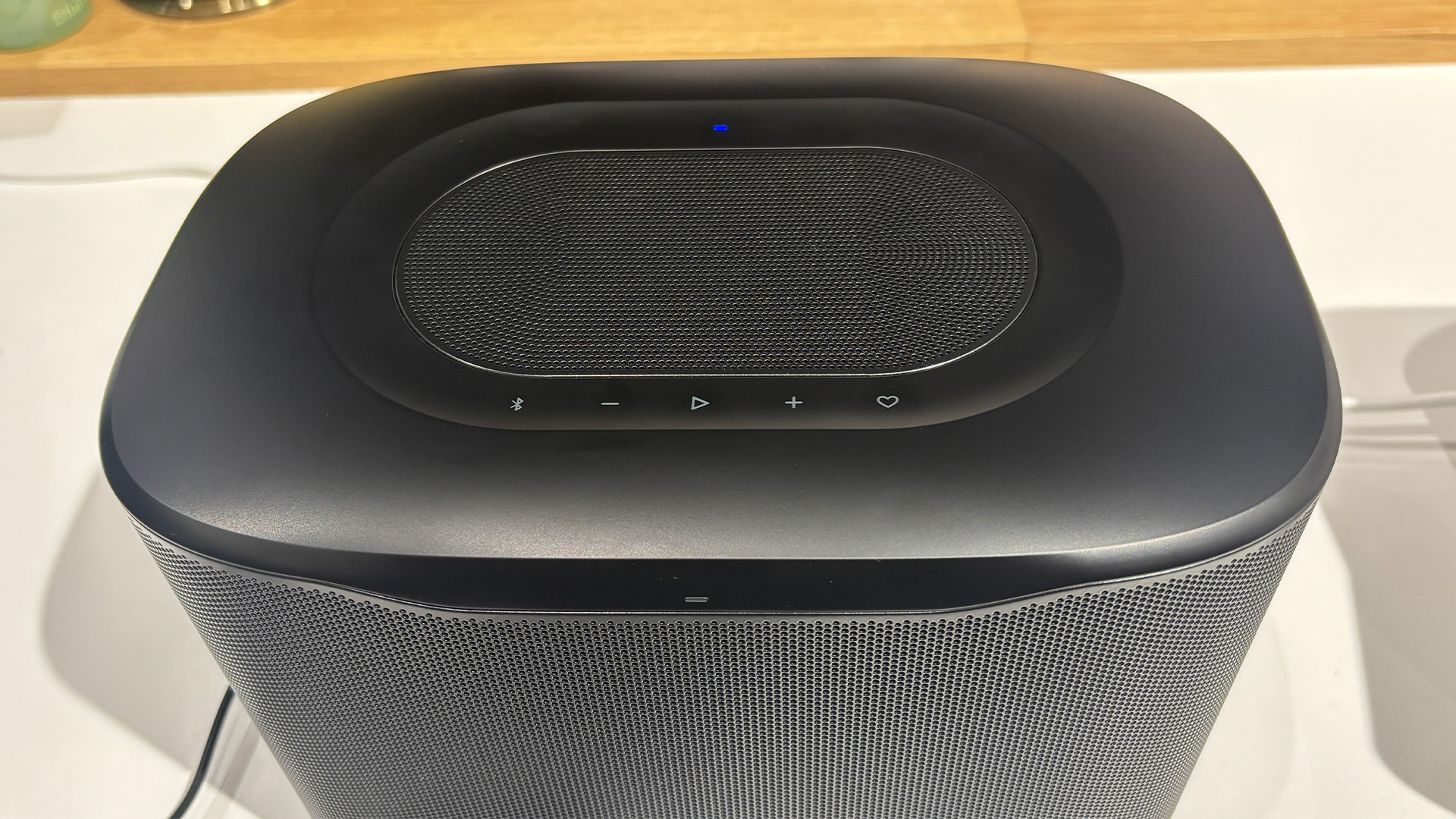 JBL Cove X1 multi-room wireless speaker on white table detail of top of speaker and controls