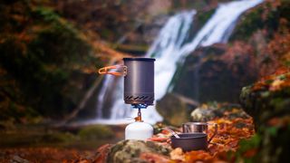 A camping stove with a waterfall behind it