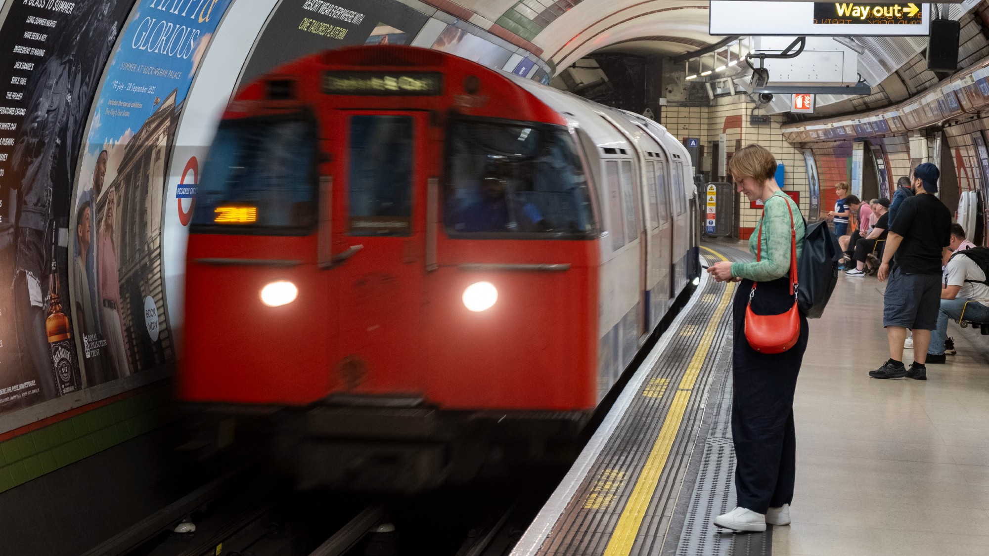 A London Underground train pulls in to the platform at Piccadilly Circus station where passengers are waiting