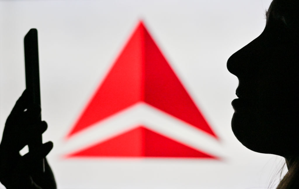 The silhouette of a woman using a smartphone in front of the Delta log.