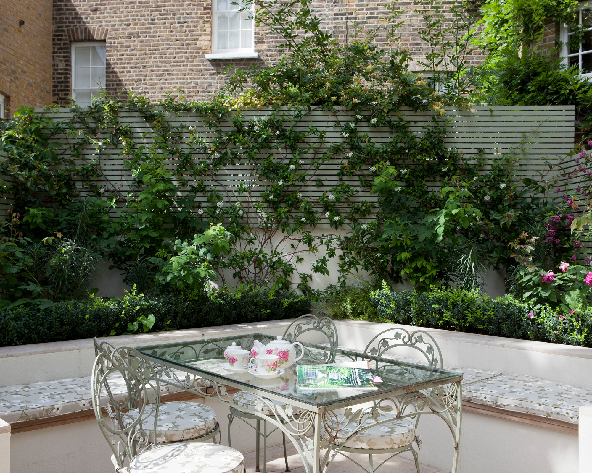 Patio planting ideas with built-in seating and dining table in a town garden.