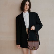 A person in a blaxer with a brown handbag.