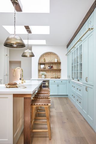kitchen with long narrow island pale blue cabinets wooden floor and bar stools