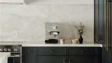Image of a concrete coffee machine on a white marble countertop that matches the backsplash and black cabinetry underneath.