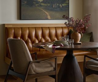 Magnolia dining room with a leather sofa, table, and vase of flowers