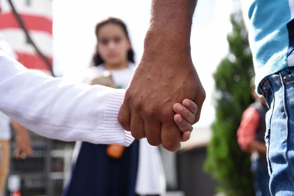 A father holds his daughter&amp;#039;s hand.