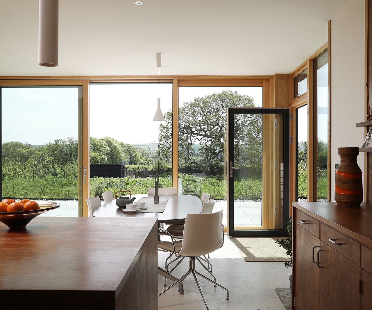An open plan kitchen dining room area with wooden cabinets and kitchen island and wooden framed sliding doors