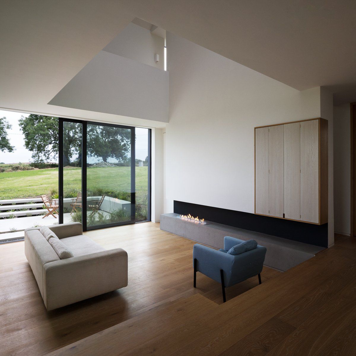 Inside an open plan house with white walls and large windows