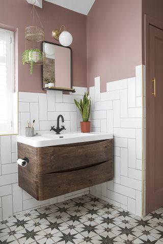 Bathroom with wall-hung wood vanity unit, white sink, pink wall paint, white metro tiles and patterned floor tiles