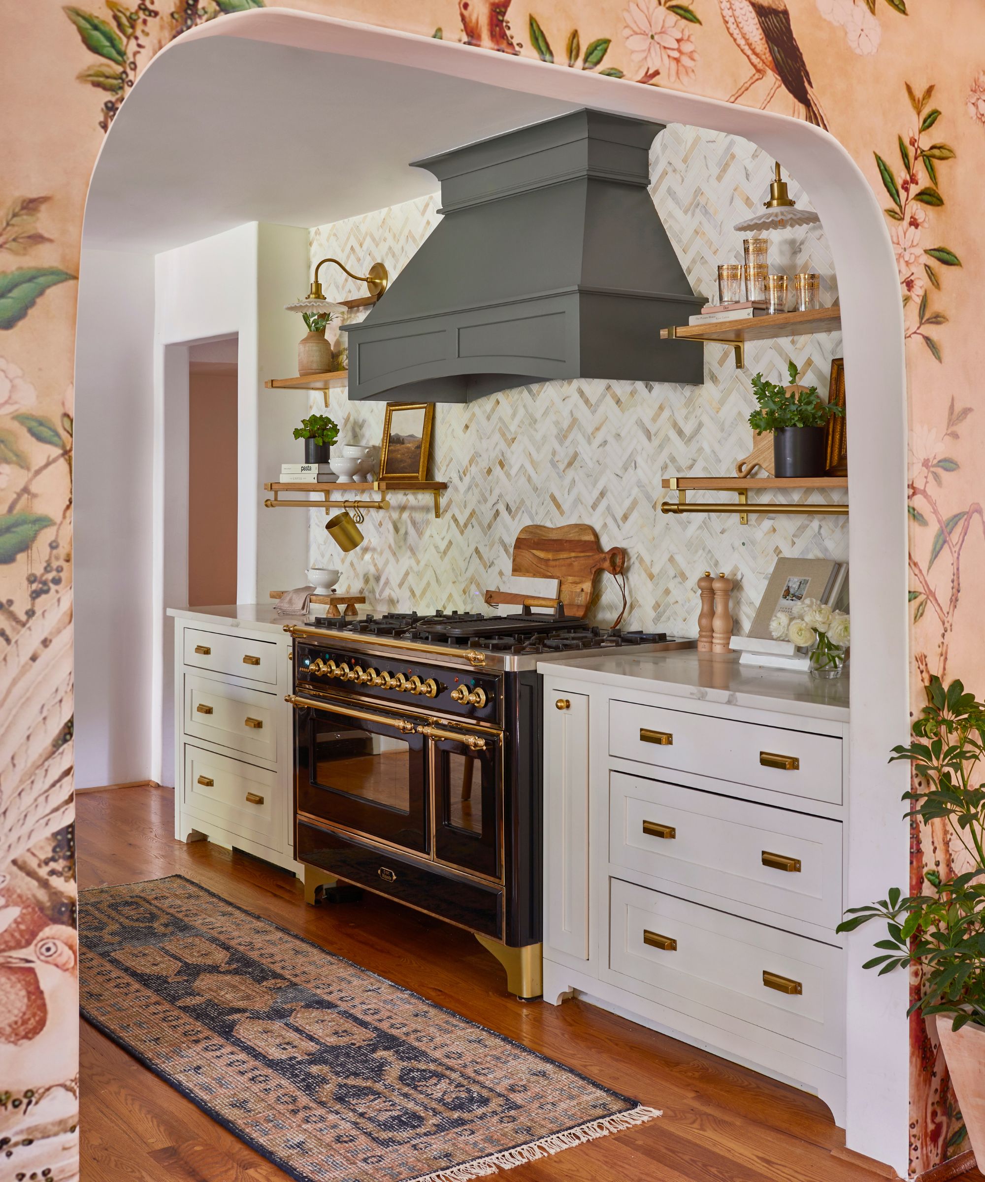 kitchen with white cabinets, tiled backsplash, and pink wallpapered arched wall in adjoining room