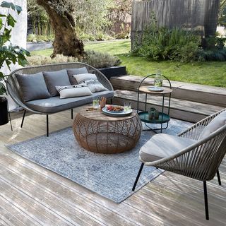 outdoor living area with sofa, tables and an outdoor rug