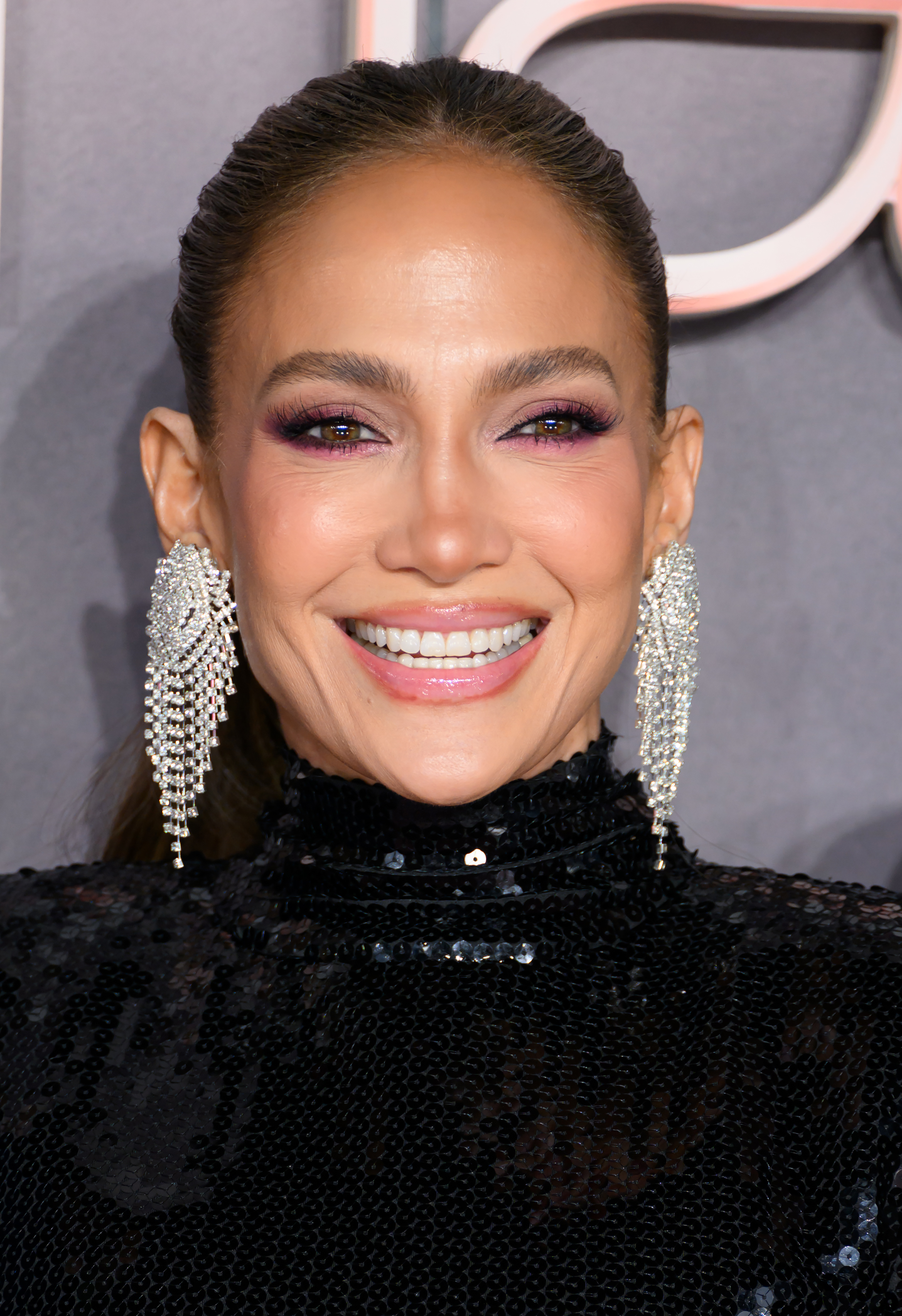 jennifer lopez wearing pink eye makeup and a pink and black gown during a red carpet event