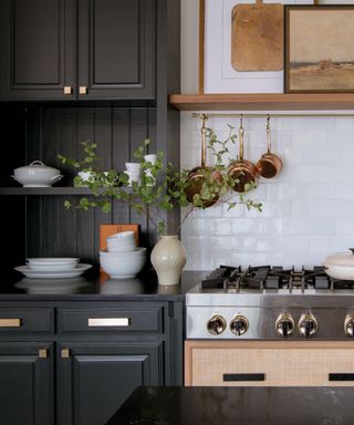should I use handles or knobs on kitchen cabinets, charcoal kitchen cabinets, with white tile backsplash, brass hanging rail, open shelving/custom cabinets