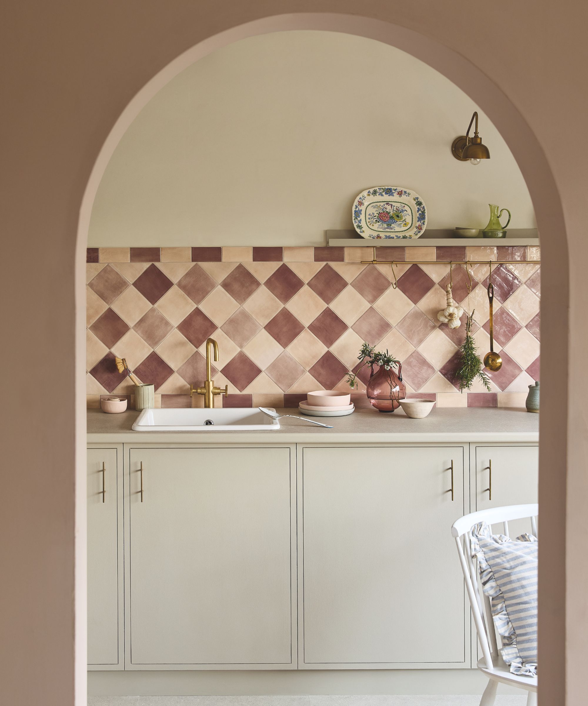 A neutral kitchen with warm white cabinets, a neutral countertop, and pink backsplash tiles