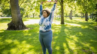 Woman doing banded shoulder-press in park with resistance band