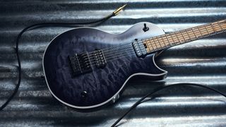 A Jackson Signature Sleep Token IV Monarkh electric guitar on a piece of corrugated metal with a guitar cable coiled nearby