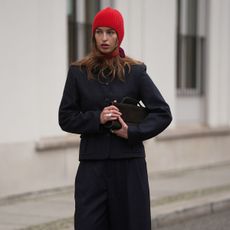 a model wearing a red cashmere bonnet and navy suit