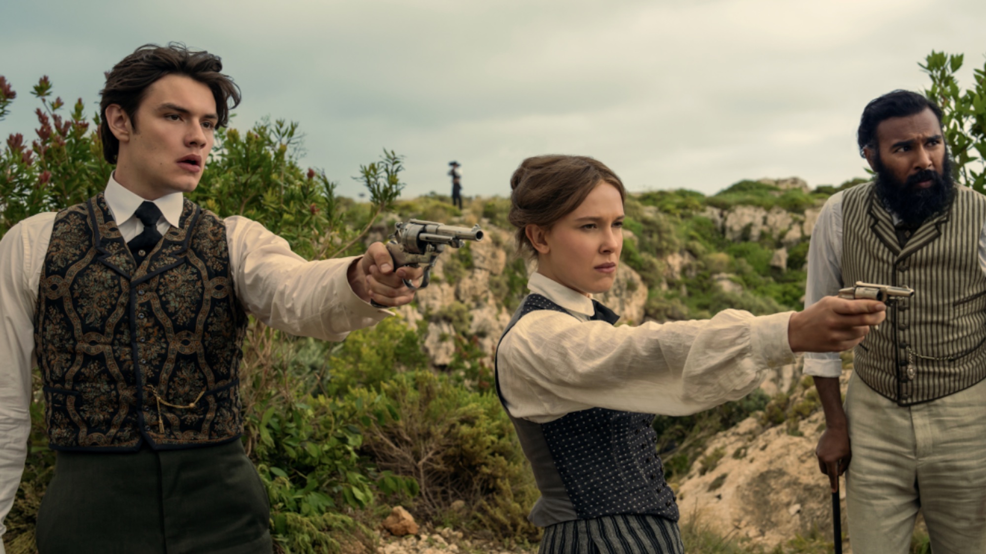 Enola and Tewksbury holding out guns in Enola Holmes 3.