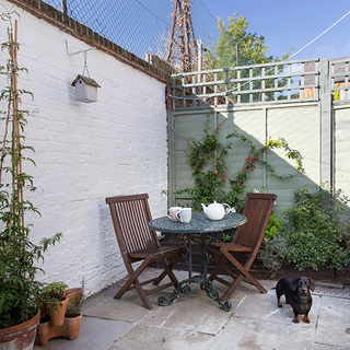 courtyard garden with white brick wall and table with chair