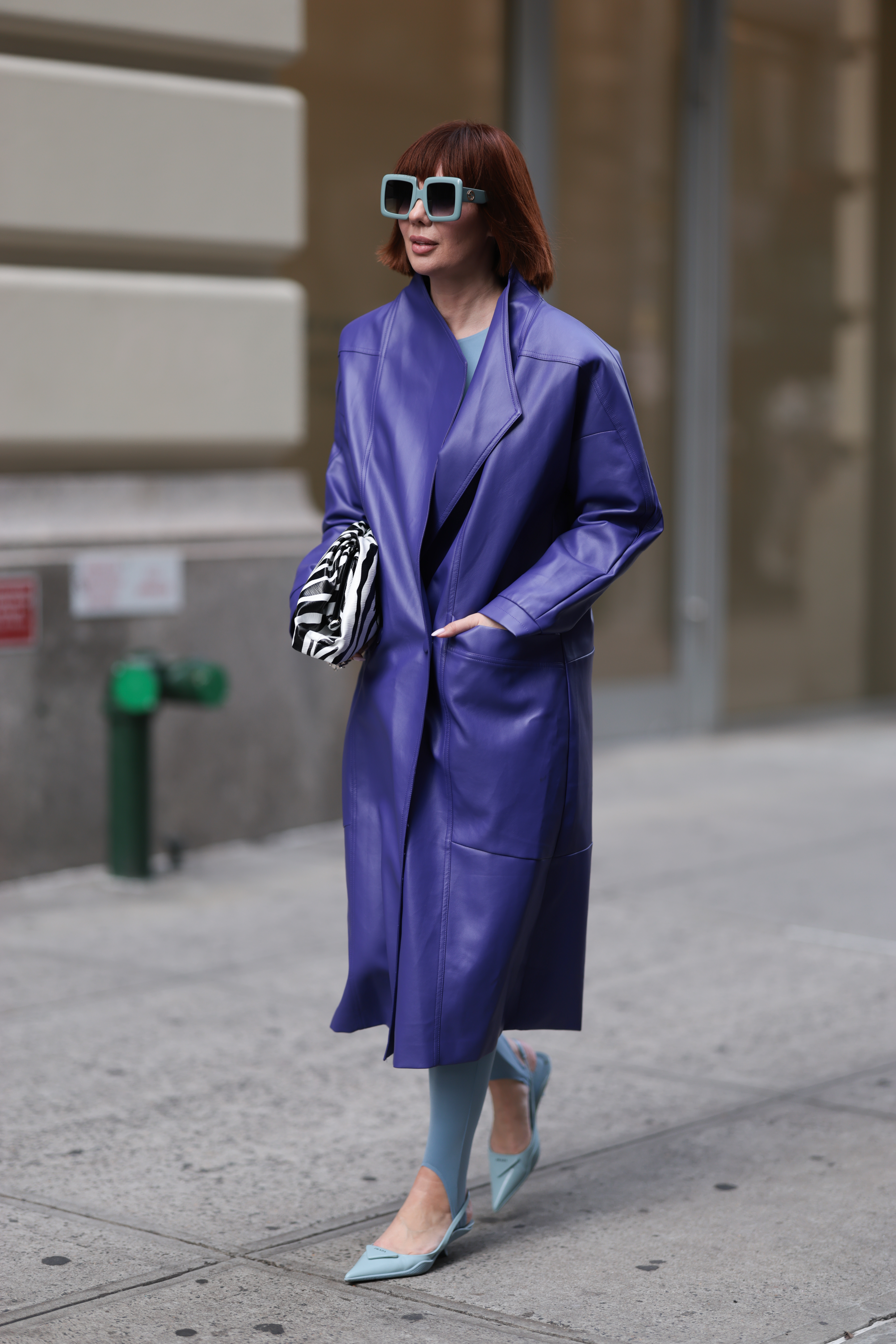 Anna Estrin wearing a purple leather coat, zebra print bag and dark sunglasses