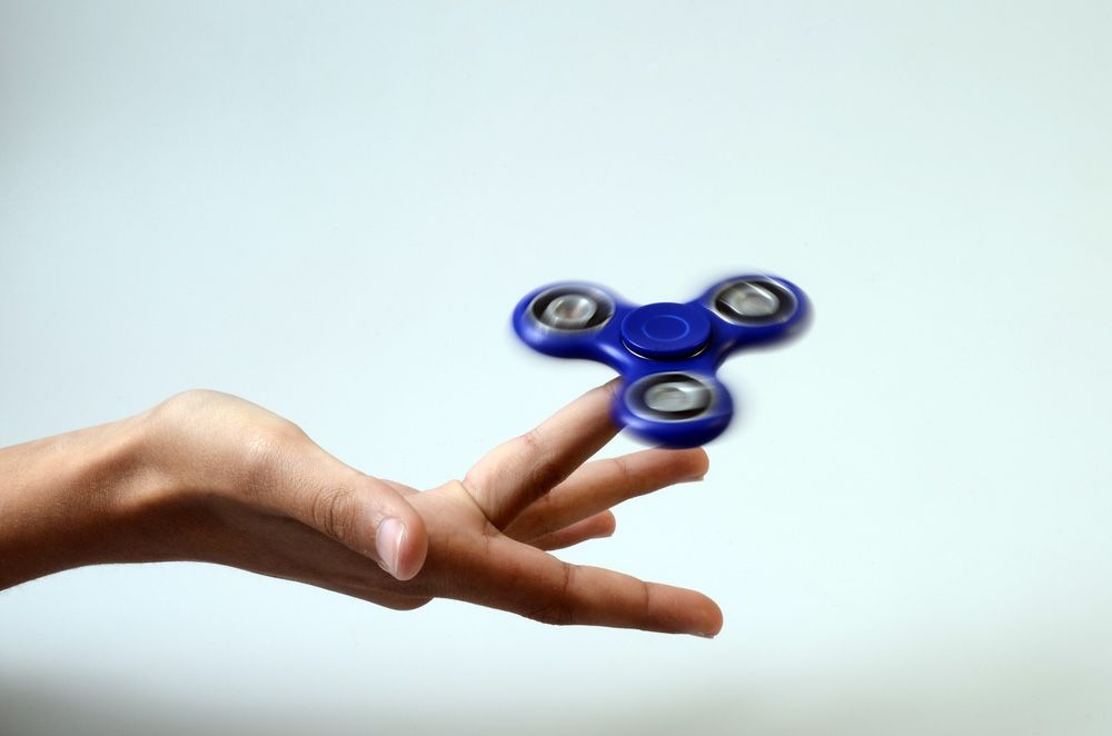 Blue fidget spinner on someone&#039;s hand.