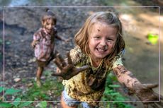 Smiling children engaging in messy play - they are covered in mud, playing outdoors