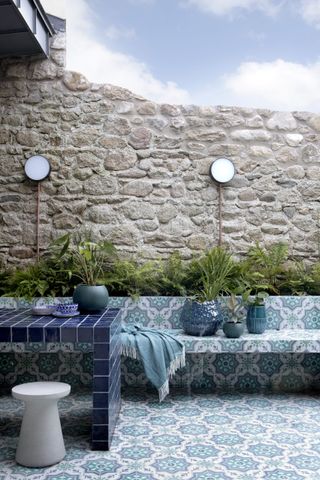 Blue tiled garden with stone wall and planters