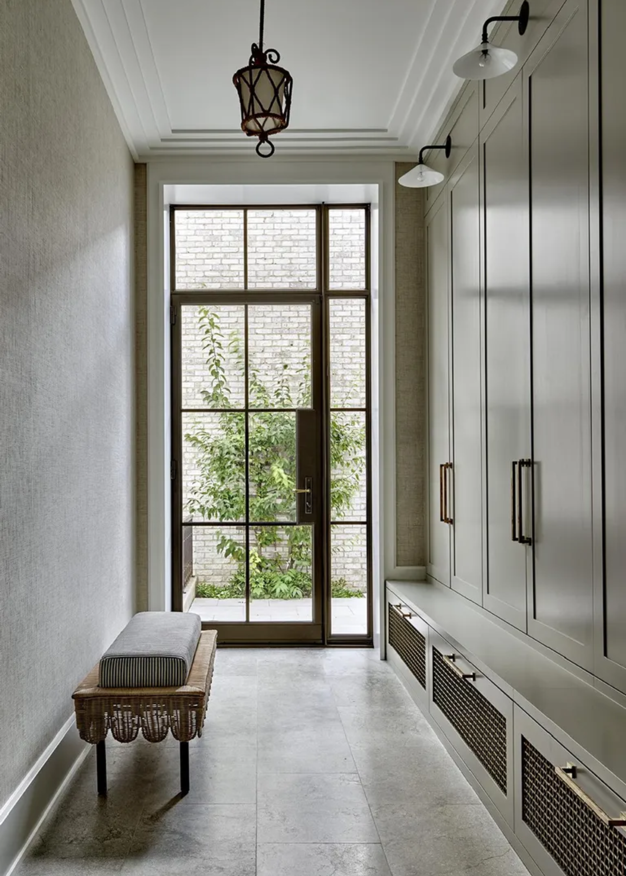 A minimalist walk-in wardrobe with overhead lighting and a bench