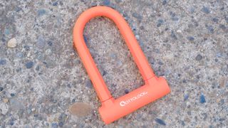 Ottolock Sidekick Compact U-lock in orange sitting on pavement 