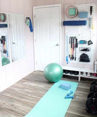 small yoga studio and DIY home gym with blue yoga mat, weights and exercise ball - Lela Burris