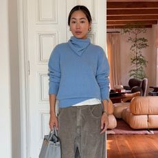 A woman wearing a blue sweater and gray pants