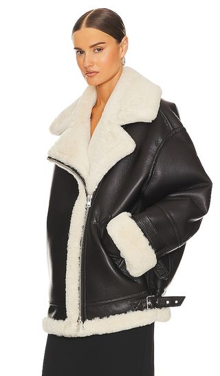 a model wears the 80s Oversized Faux Shearling Jacket by Helsa in front of a plain backdrop
