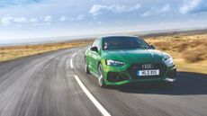 A green Audi RS5 plug-in hybrid on a countryside road